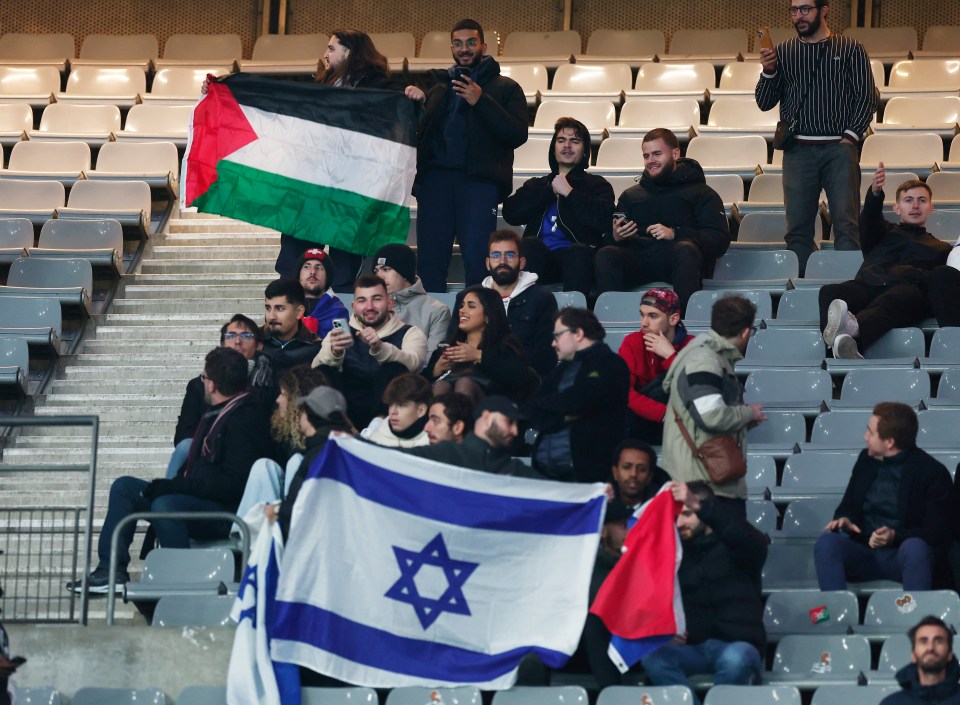 a group of people sitting in a stadium holding flags