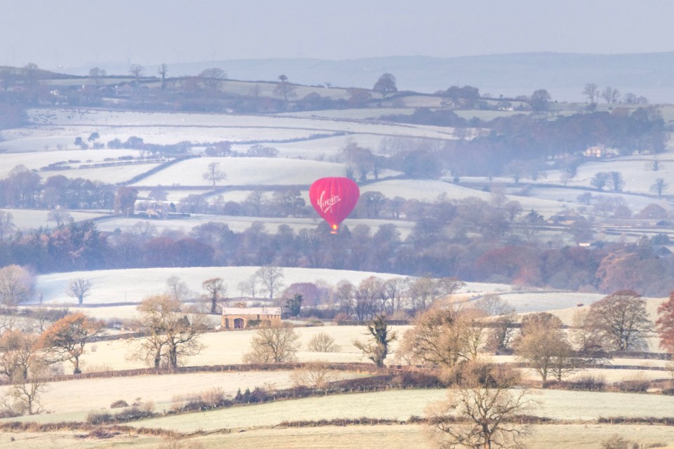 a virgin hot air balloon flies over a snowy landscape
