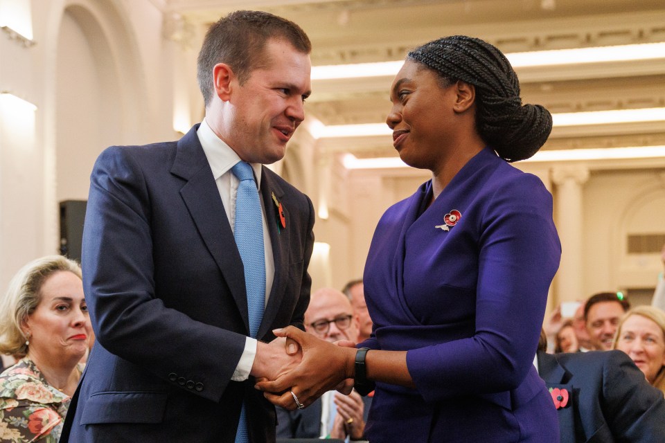 a man in a suit and tie shakes hands with a woman in a purple dress