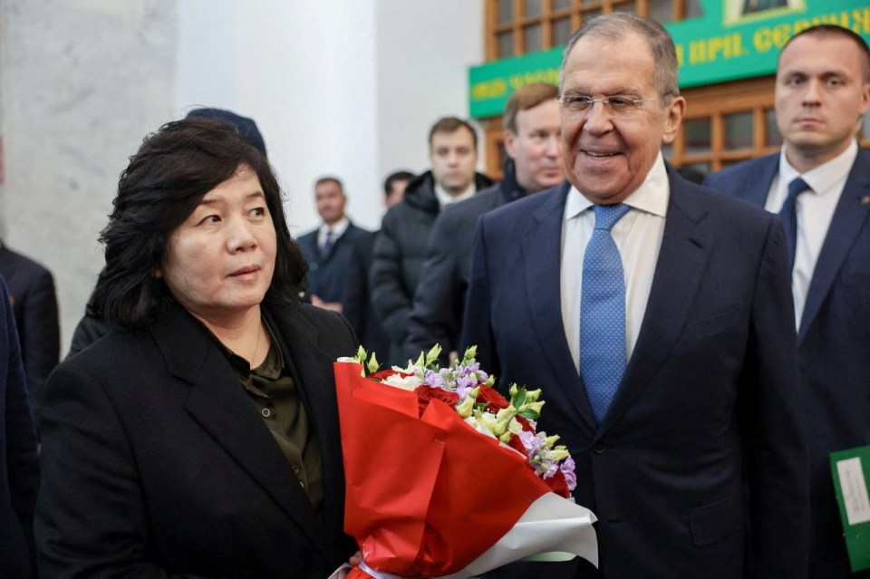 a man in a suit and tie stands next to a woman holding a bouquet of flowers
