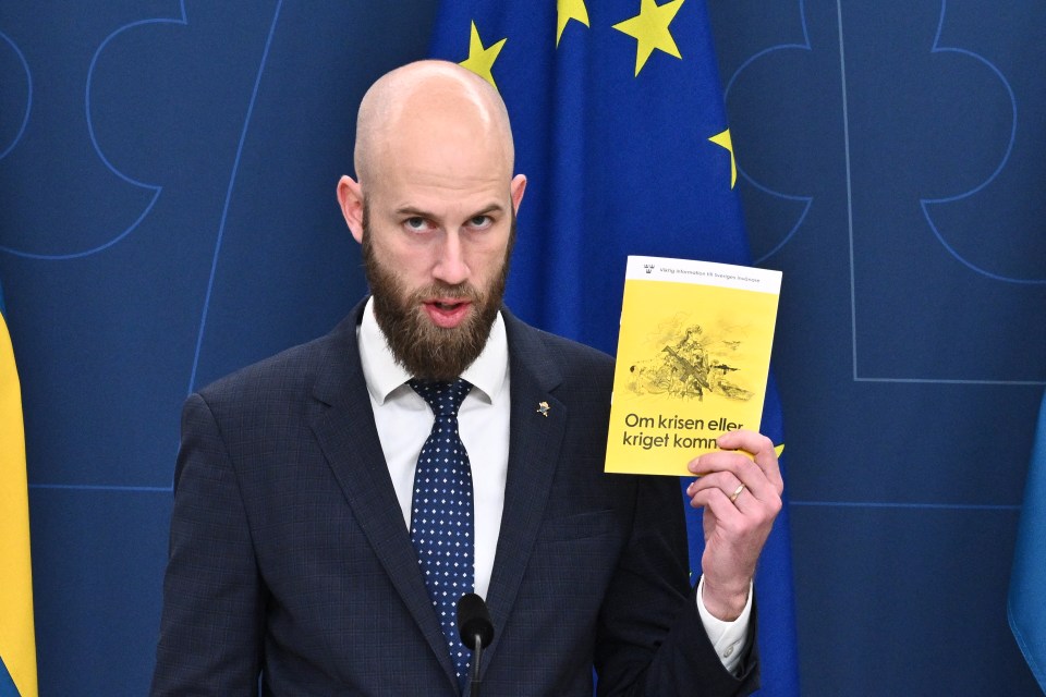 a man in a suit and tie is holding a book that says om krisen eller krigel kommer