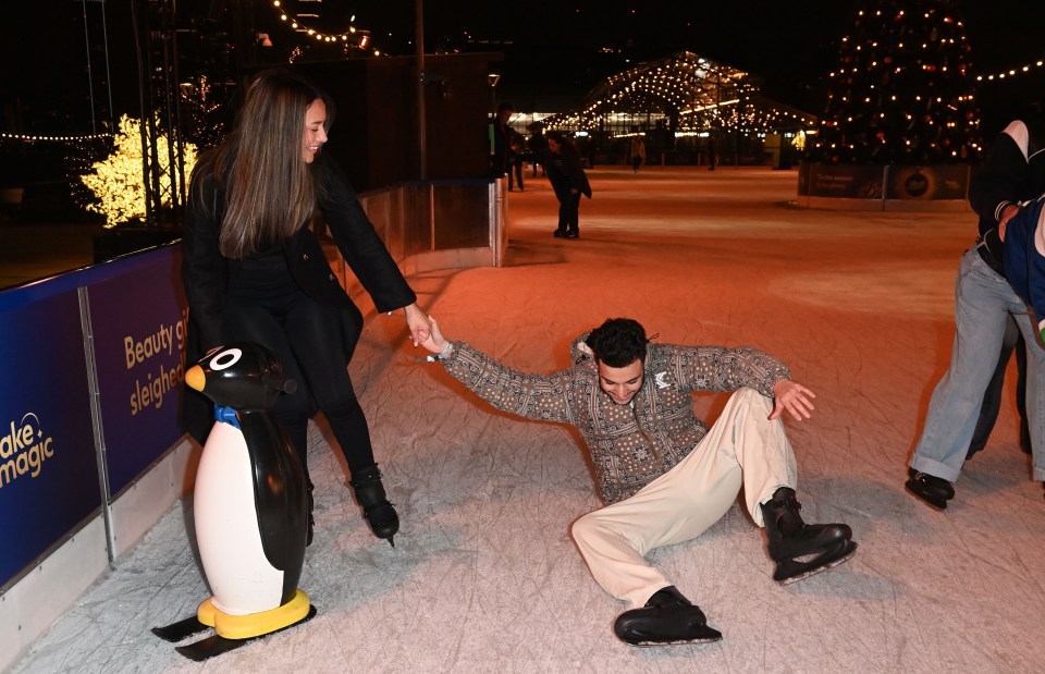 a man is laying on the ice while a woman helps him up