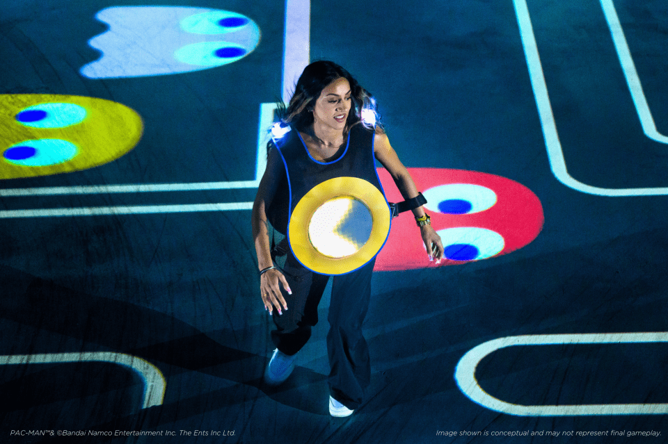 a woman in a pac man costume stands in front of a projector screen