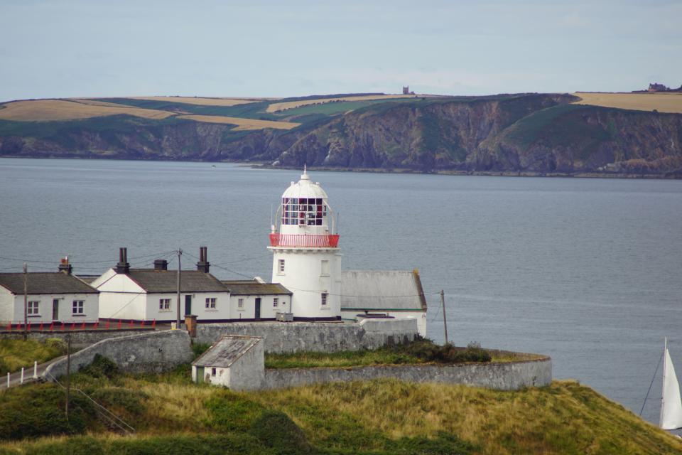 a lighthouse sits on a hill overlooking the ocean