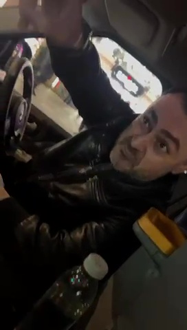 a man is driving a car with a bottle of water in the back seat .