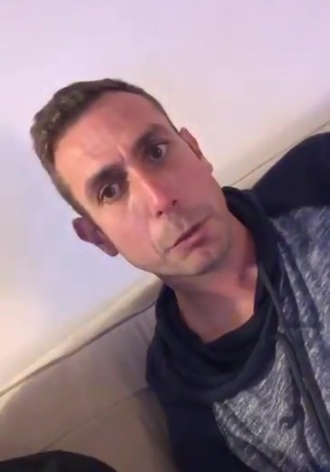 a man is sitting on a couch making a funny face .