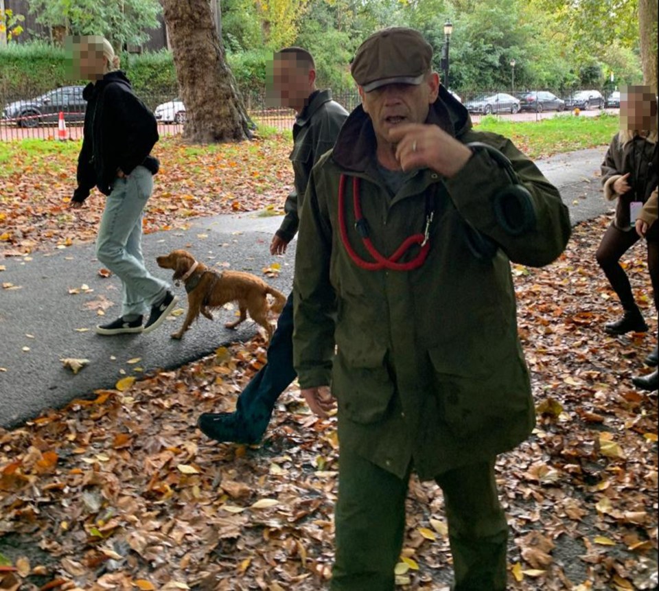 a man in a green jacket is walking a dog on a leash