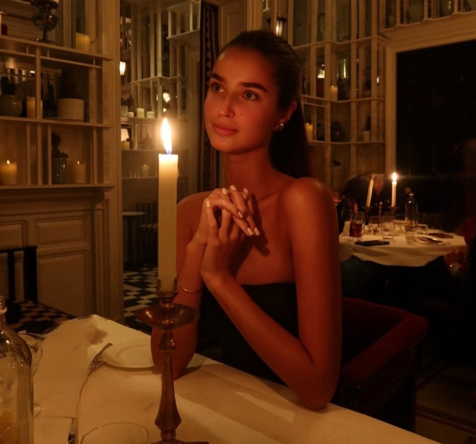 a woman sits at a table with a lit candle