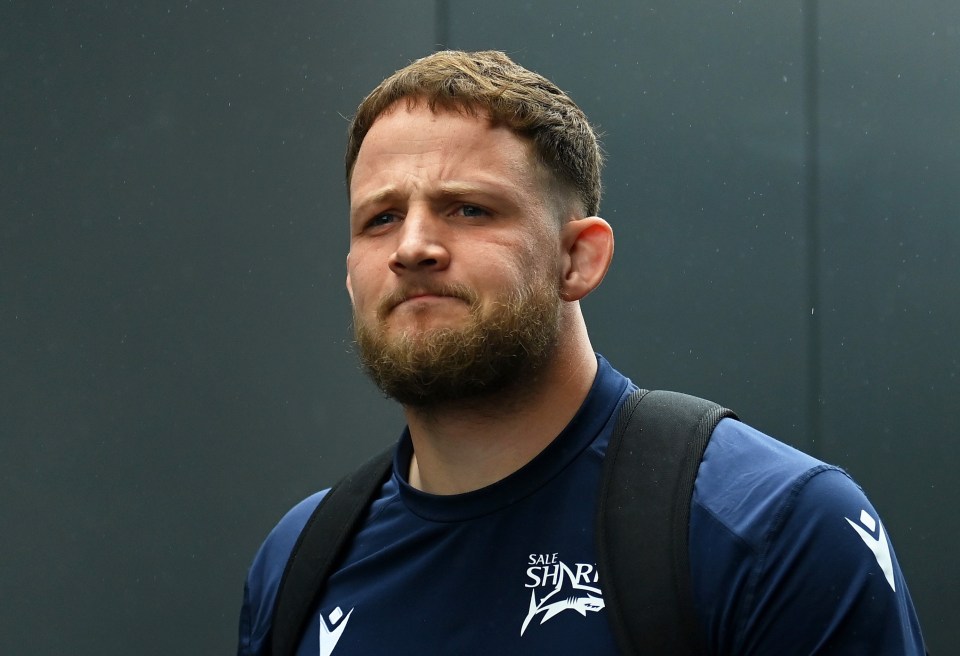 a man with a beard wears a blue shirt that says the sharks