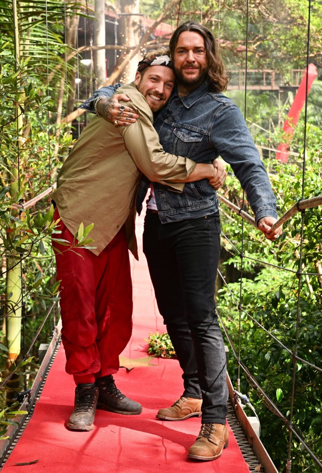 two men hugging each other on a red carpet