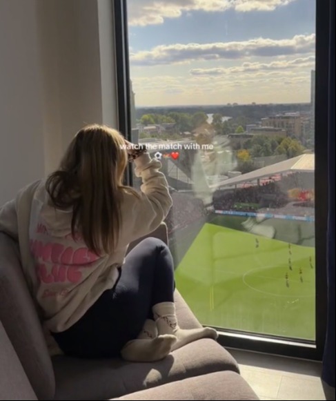 a girl sitting on a couch watching a soccer game