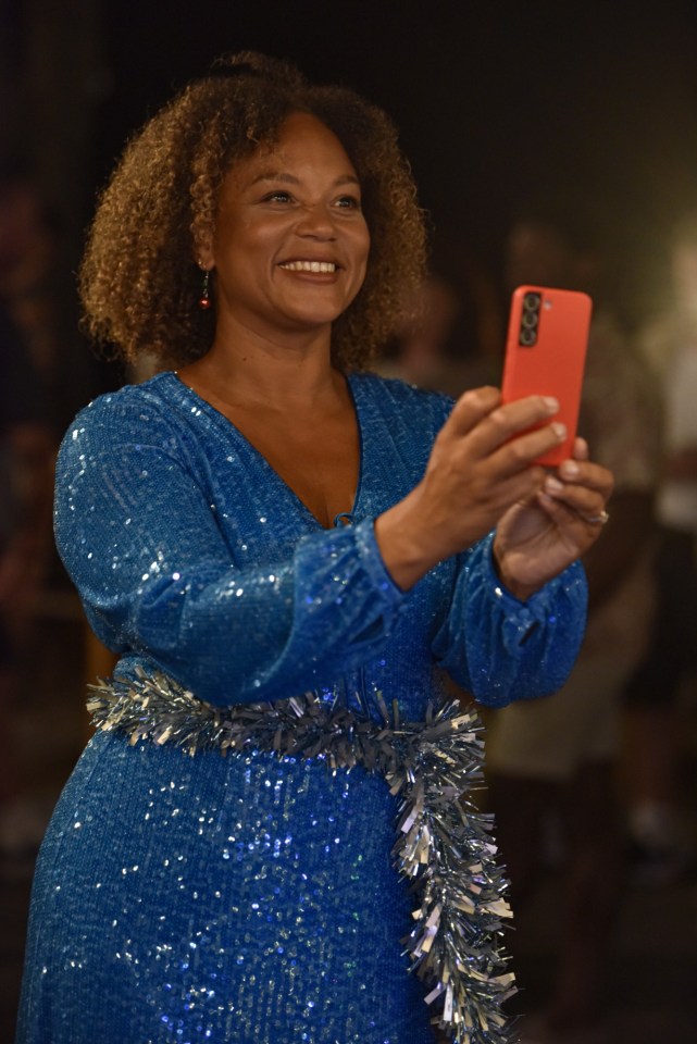 a woman in a blue sequined dress is taking a picture with her phone