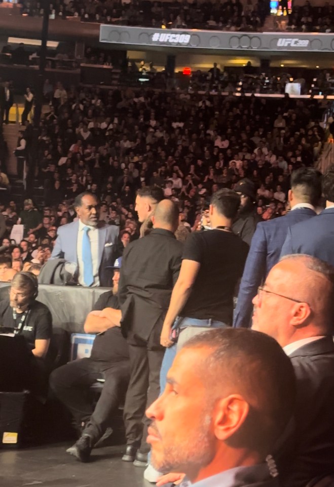 a man in a suit stands in front of a ufc sign