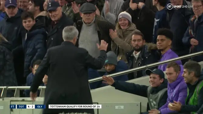 a soccer player is shaking hands with a fan in the stands .