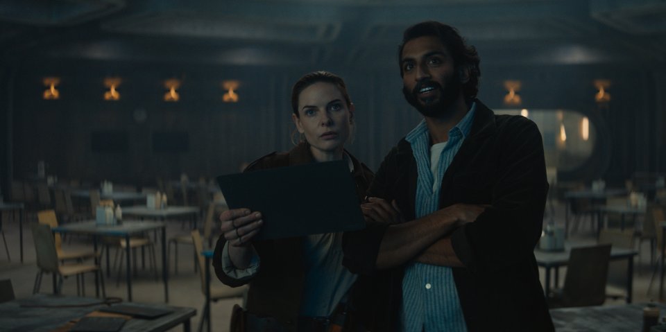 a man and a woman looking at a piece of paper in a dark room
