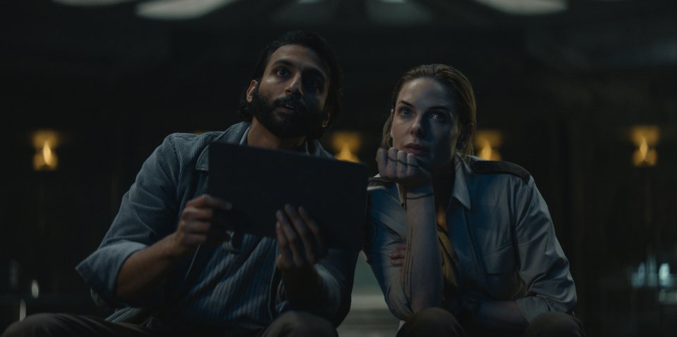 a man and a woman looking at a tablet in a dark room