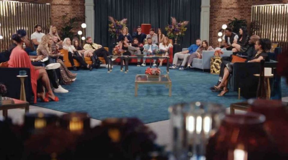 a group of people are sitting around a table in a living room