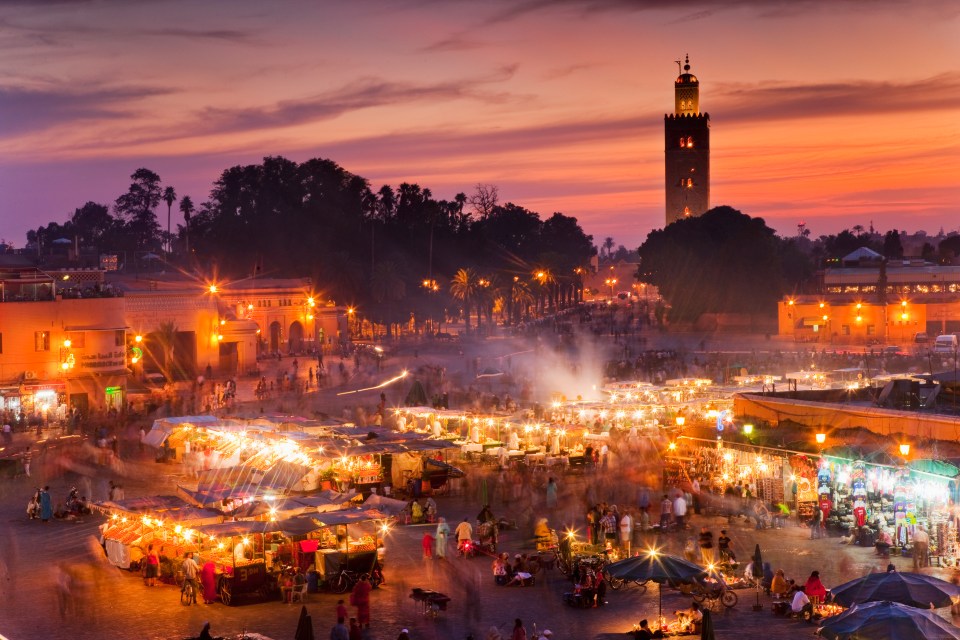 a sunset over a market with a tower in the background