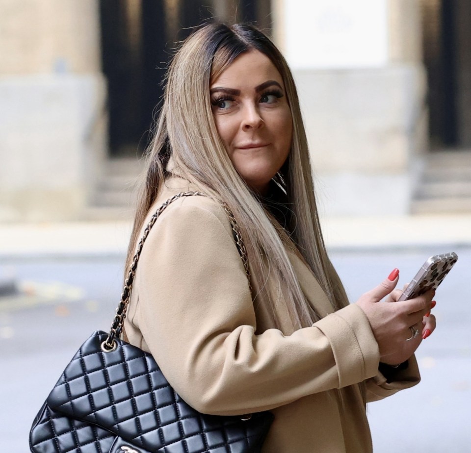 a woman wearing a tan coat and a black chanel purse