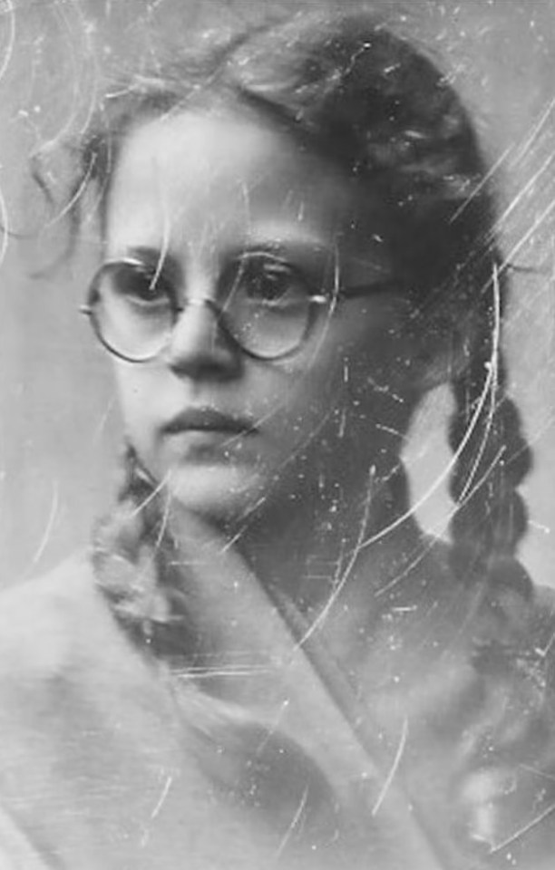 a black and white photo of a young girl wearing glasses .
