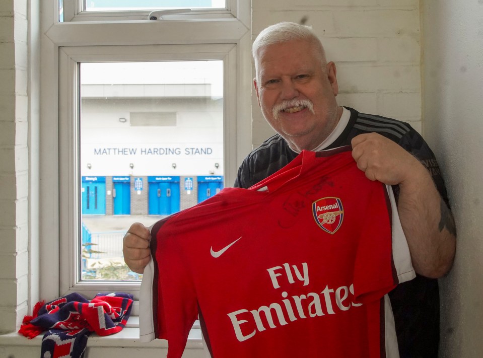 a man holds up a red fly emirates jersey