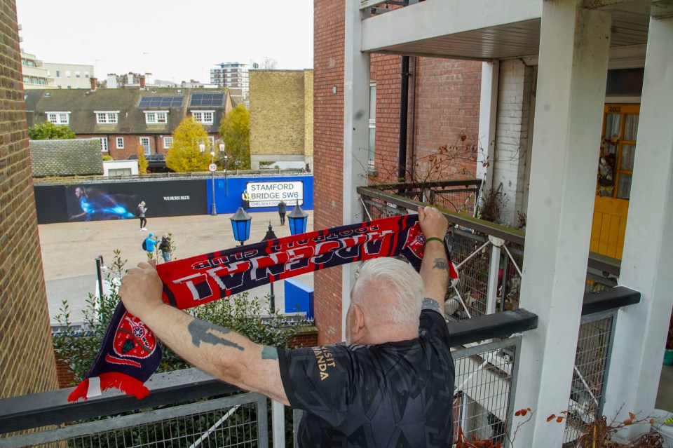 a man holds up a scarf that says arsenal on it