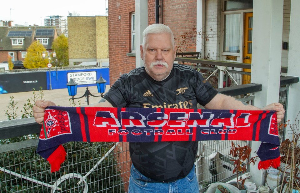 a man holding a scarf that says arsenal football club