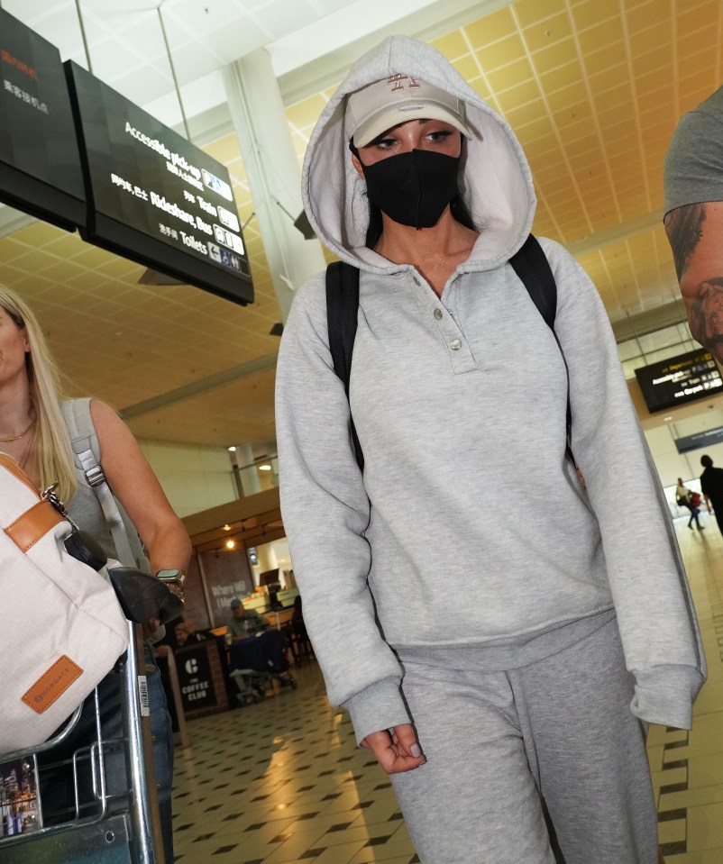 a woman wearing a mask is walking through an airport