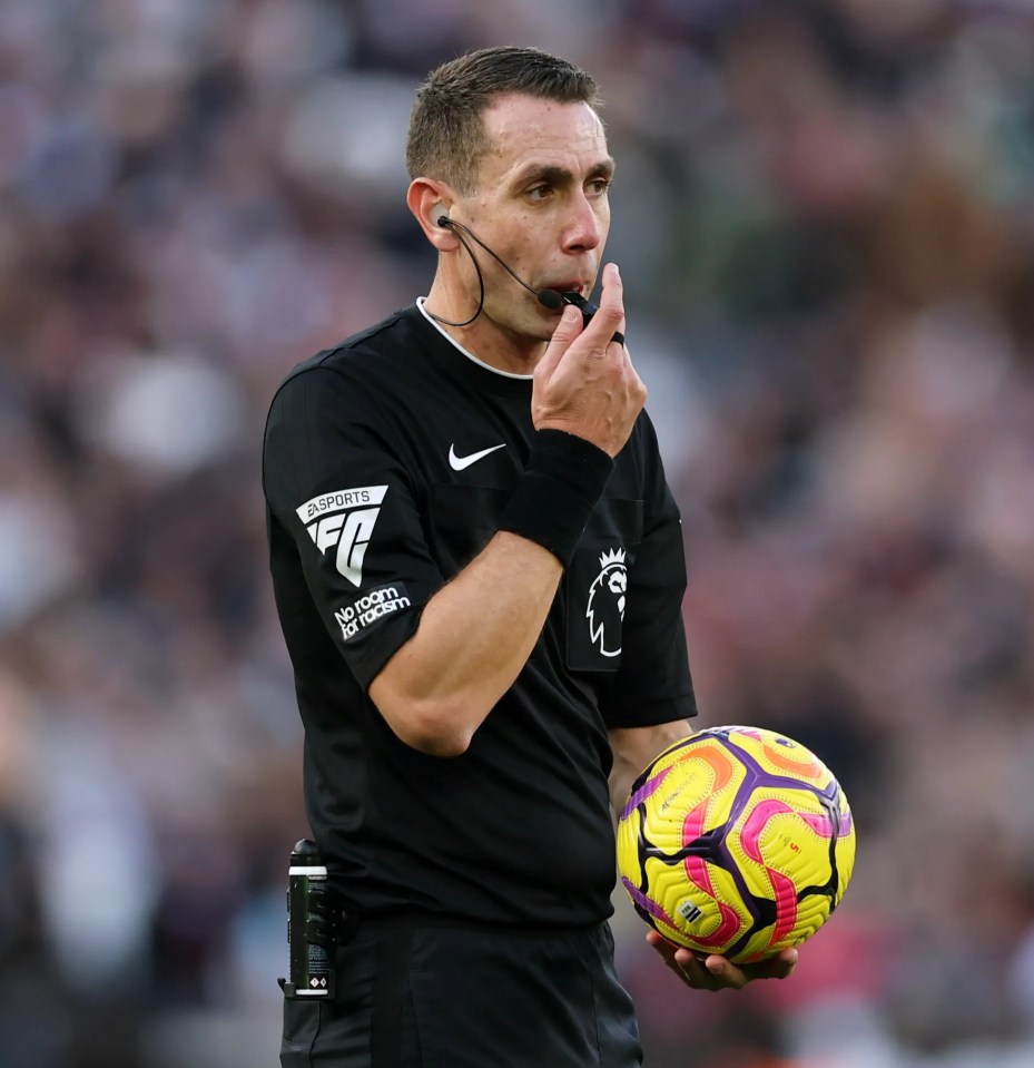 a referee holds a soccer ball while wearing a shirt that says no room for racism