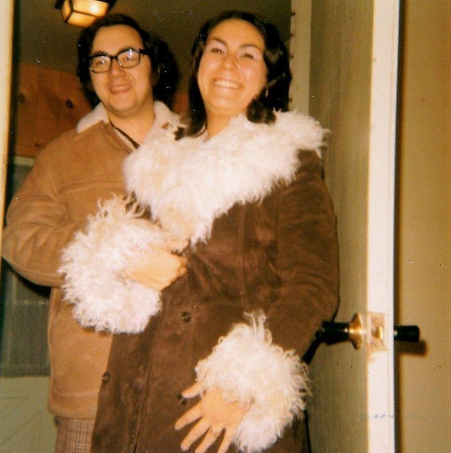 a man and a woman are posing for a picture and the woman is wearing a fur coat
