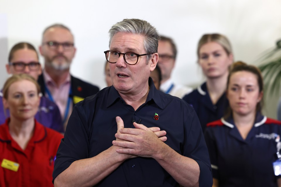 a man wearing glasses stands in front of a group of nurses