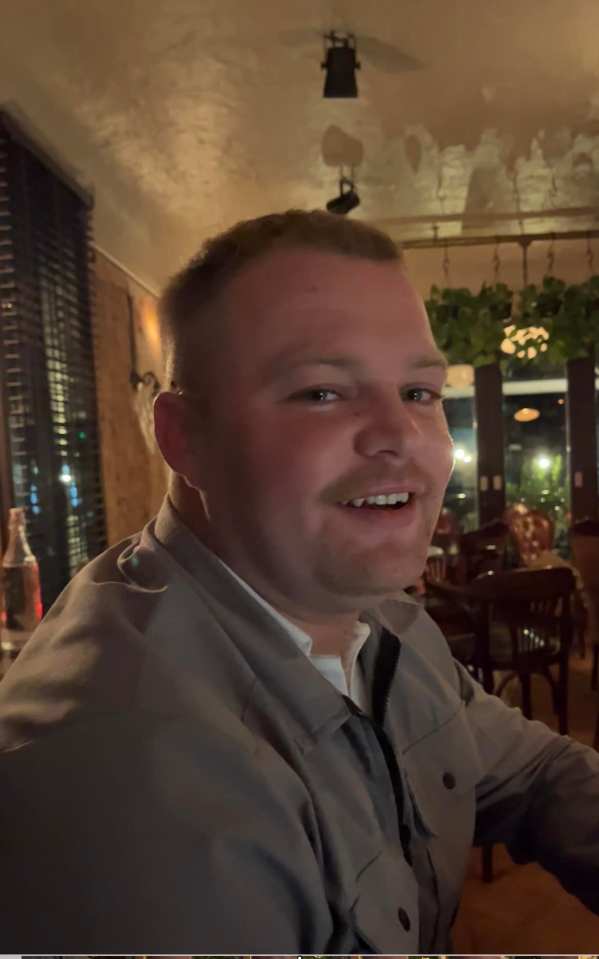 a man in a grey shirt is smiling in a restaurant