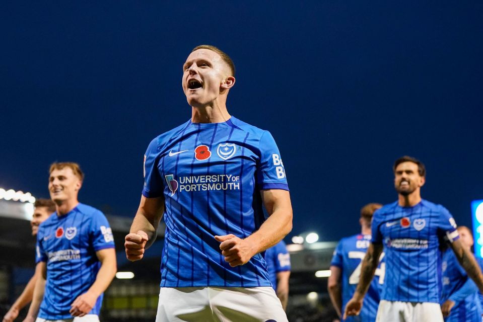 a man in a blue university of portsmouth jersey celebrates