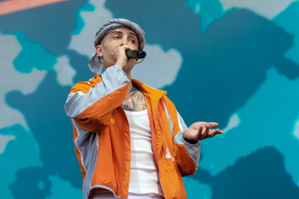a man in an orange jacket is singing into a microphone