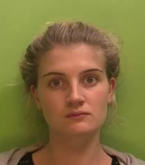 a woman is standing in front of a green wall and looking at the camera .