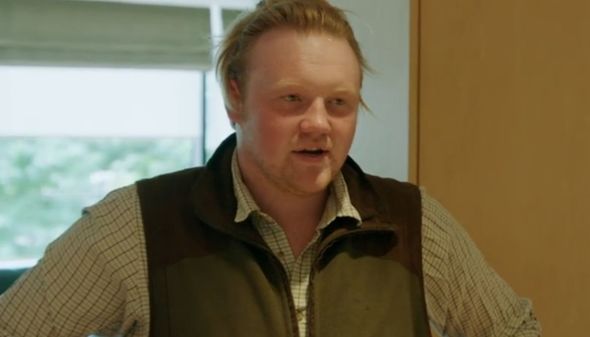 a man wearing a vest and a plaid shirt is standing in a room .