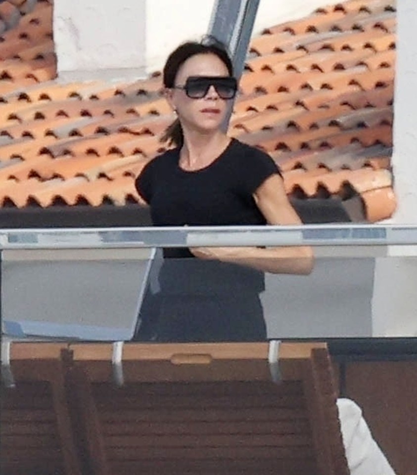 a woman wearing sunglasses and a black shirt is standing on a balcony .
