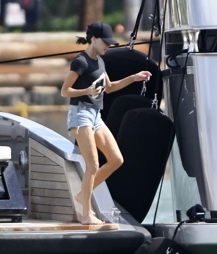 a woman wearing shorts and a black hat stands on a boat