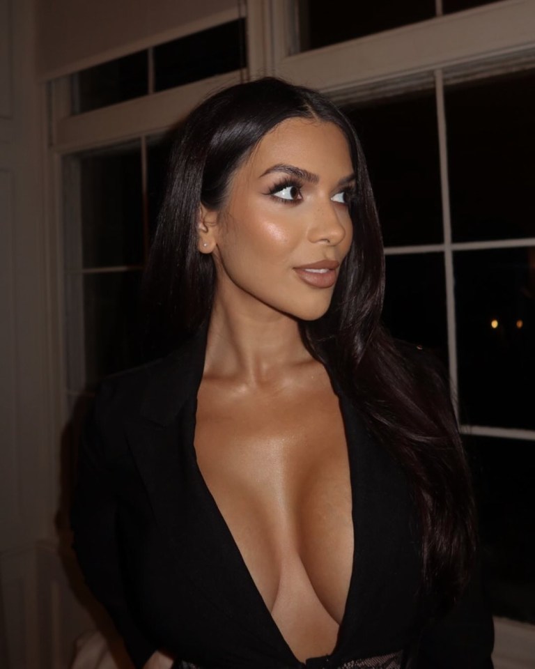 a woman with a very plunging neckline is standing in front of a window