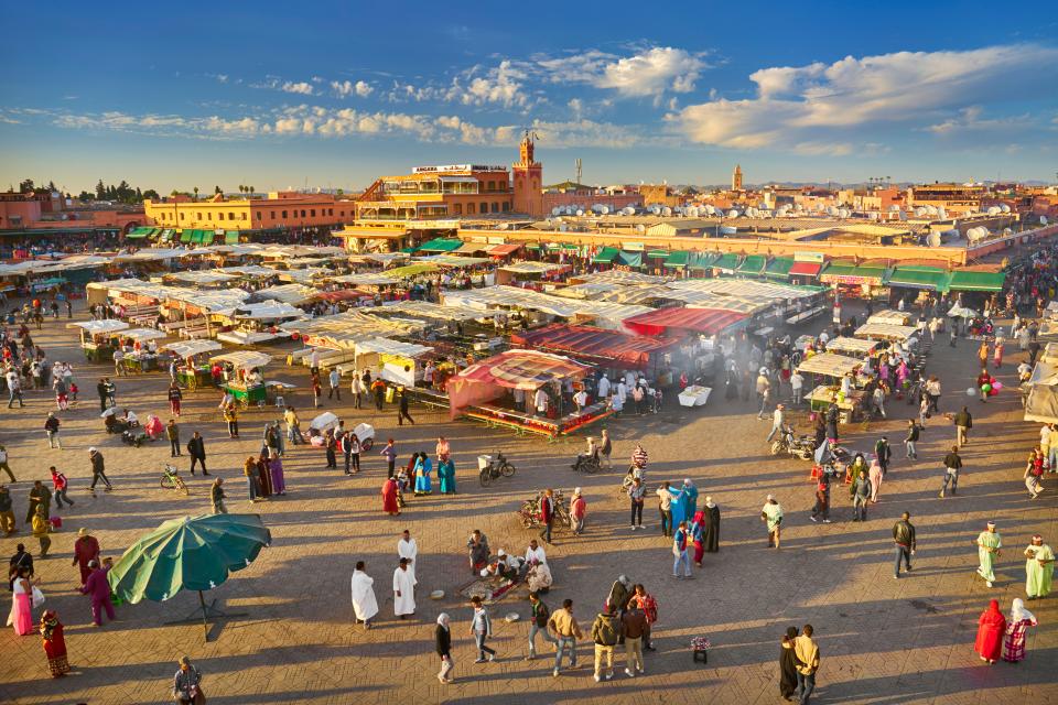 a large crowd of people are gathered in a plaza with a building that says ' sahara ' on it