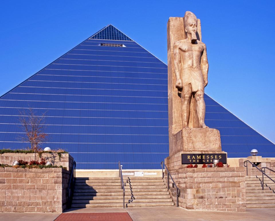 a statue of ramesses the great in front of a pyramid