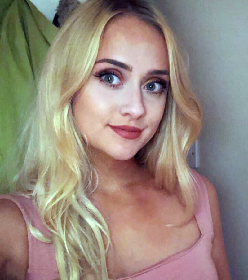 a woman with blonde hair and green eyes is wearing a pink tank top