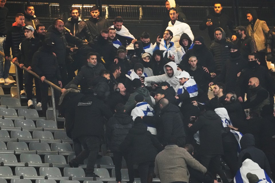 a group of people in a stadium with one wearing a yellow vest that says ' security ' on it