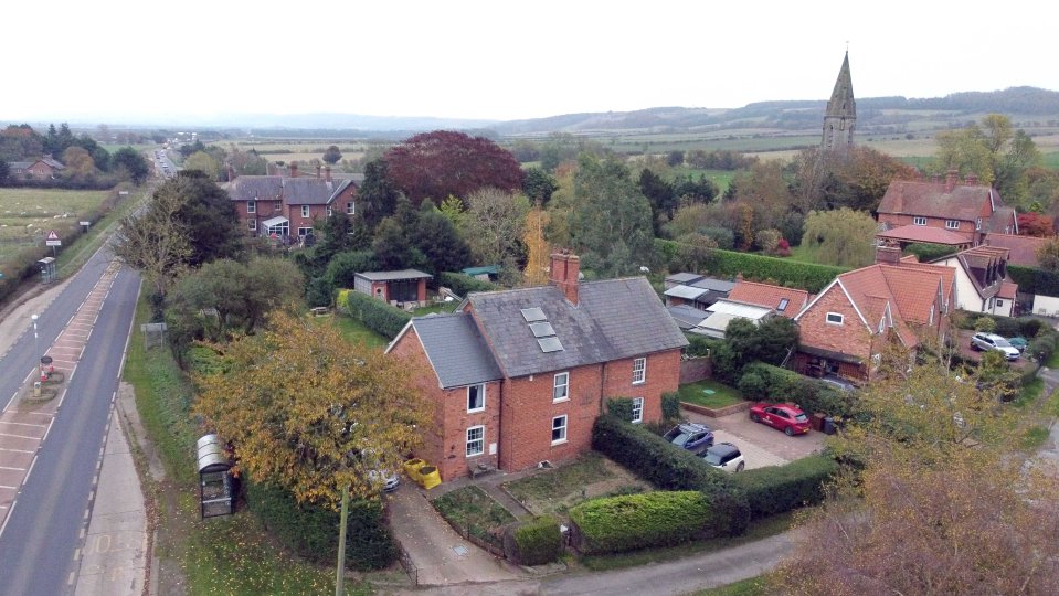 a red car is parked in front of a brick house