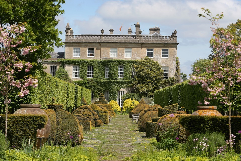 a large house is behind a lush green garden