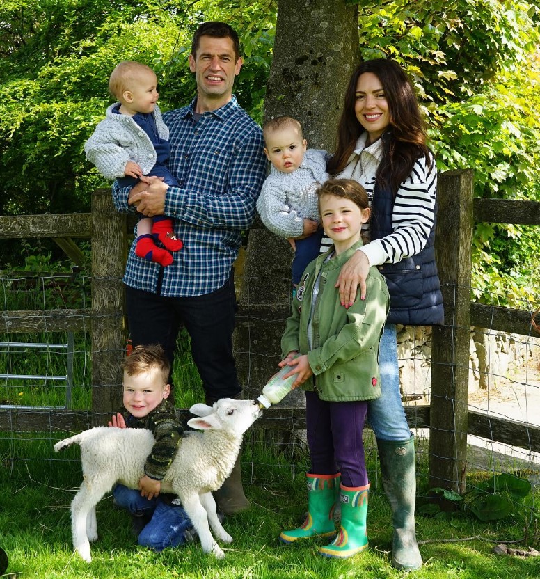 a family posing for a picture with a baby sheep