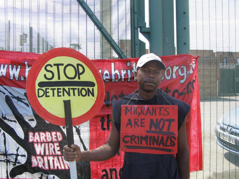 a man holding a sign that says migrants are not criminals