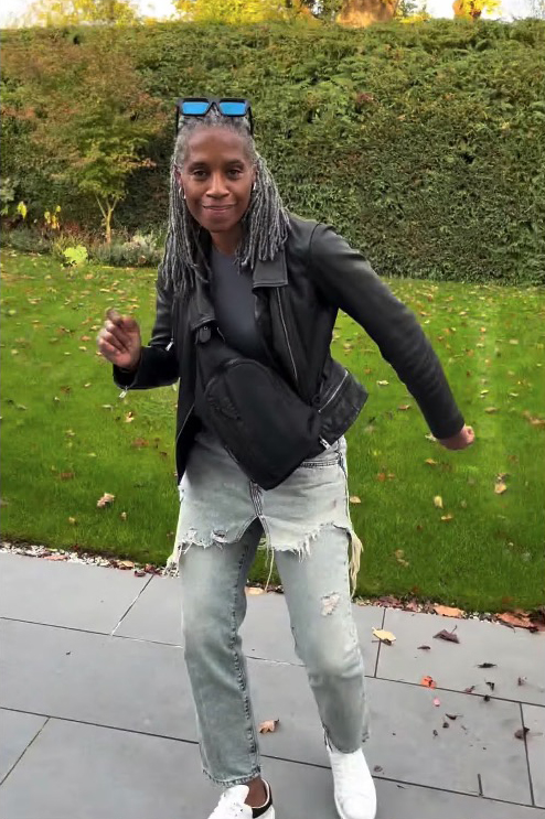 a woman wearing a black leather jacket and ripped jeans is dancing