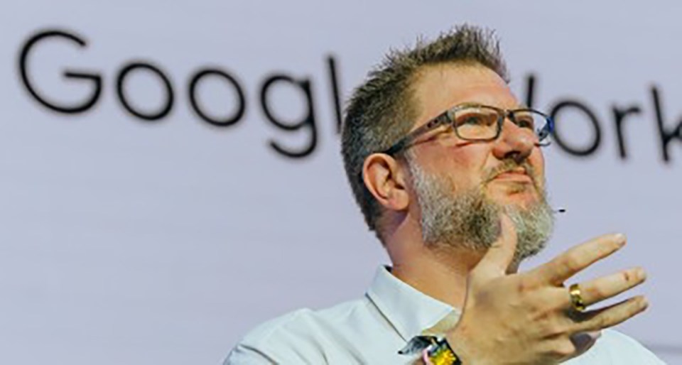 a man with glasses and a beard stands in front of a google logo