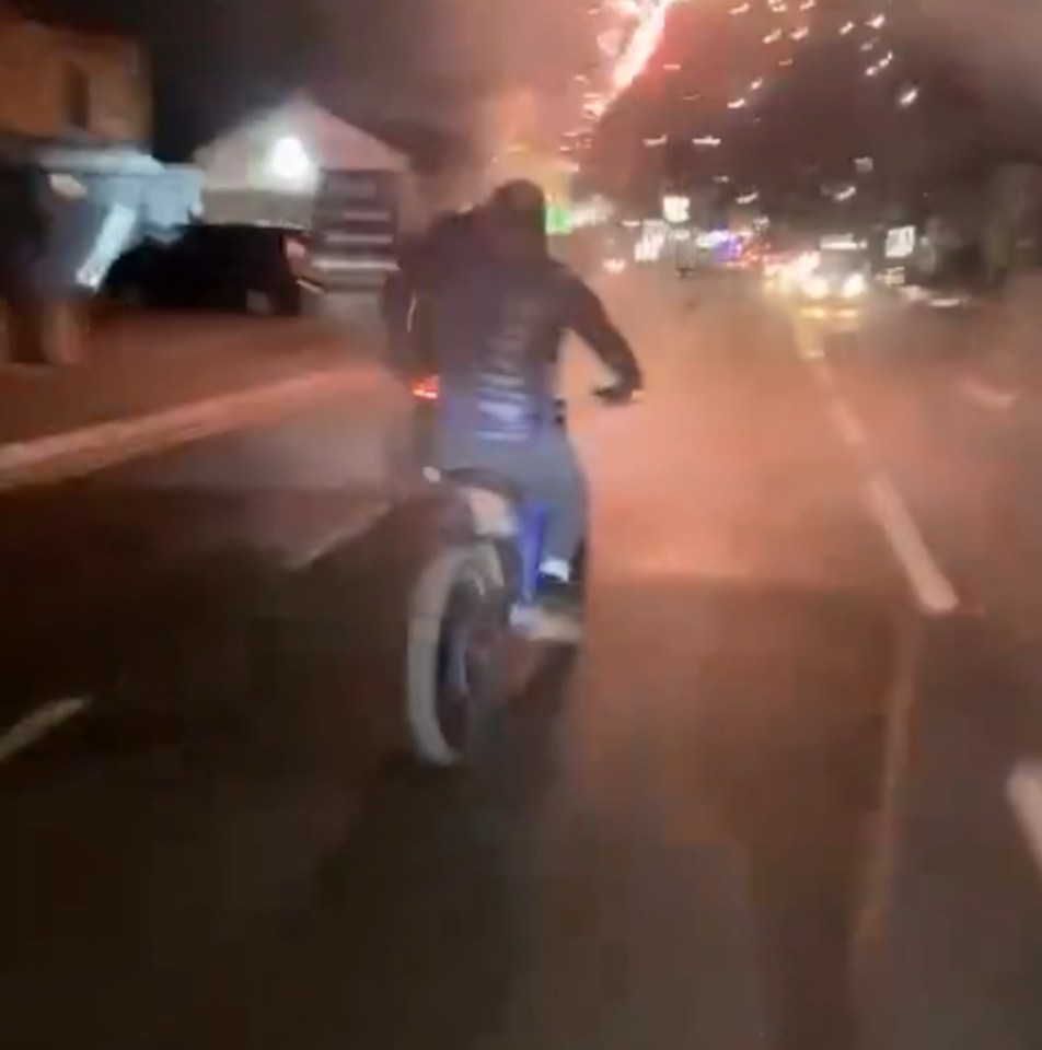 a man is riding a motorcycle down a street at night .